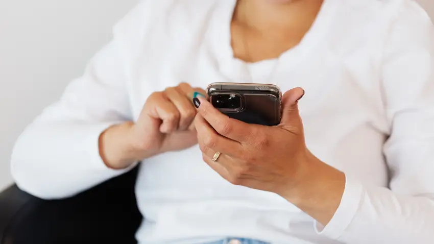 スマートフォンを使って手続きをしている女性のイメージ画像