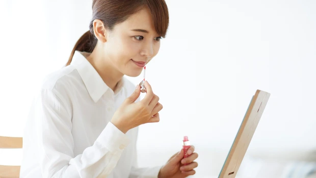 鏡を見ながらリップを塗る女性