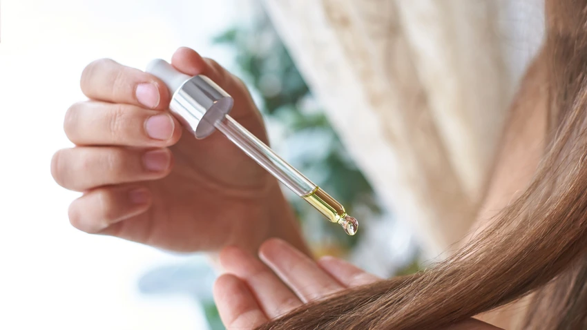 スポイトを使って髪の毛先にヘアオイルをなじませる様子