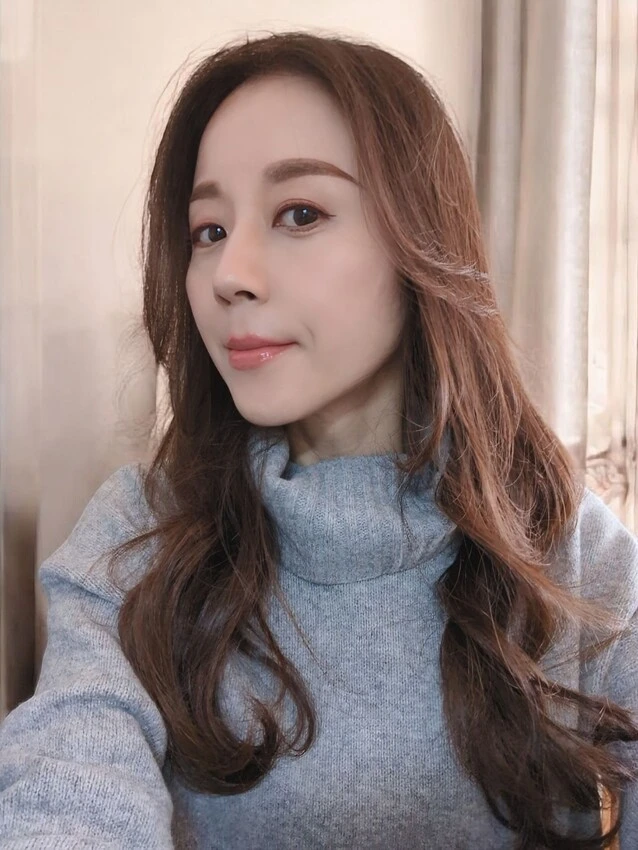 大きめでゆるやかなウェーブに巻いたロングヘアスタイルの女性